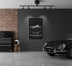 Vintage car displayed in a room with a framed poster of an Aston Martin DBS on the wall.